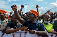 Close up photo of a group of protesters holding a banner, fists up.