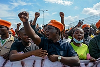 Close up photo of a group of protesters holding a banner, fists up.